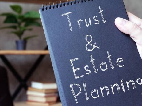 Attorney holding up a notebook labeled 'Trust & Estate Planning | Fischetti Law Group